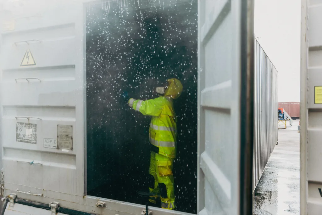 En tekniker rengör insidan av en fraktcontainer.