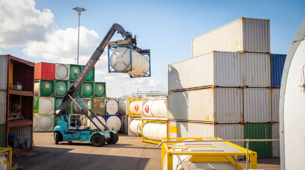 En reachstacker lyfter en tankcontainer på ett containerområde.