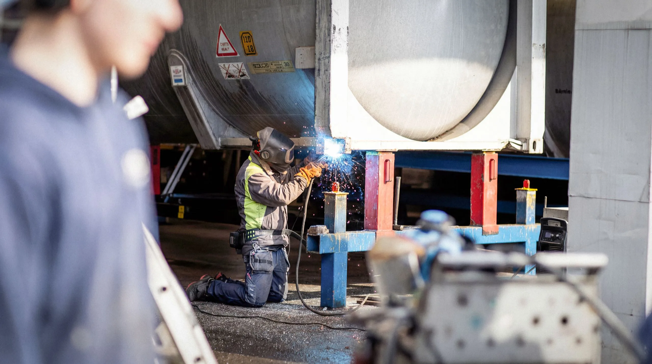 Tekniker servar en tankcontainer på Elfcons verkstadsområde.